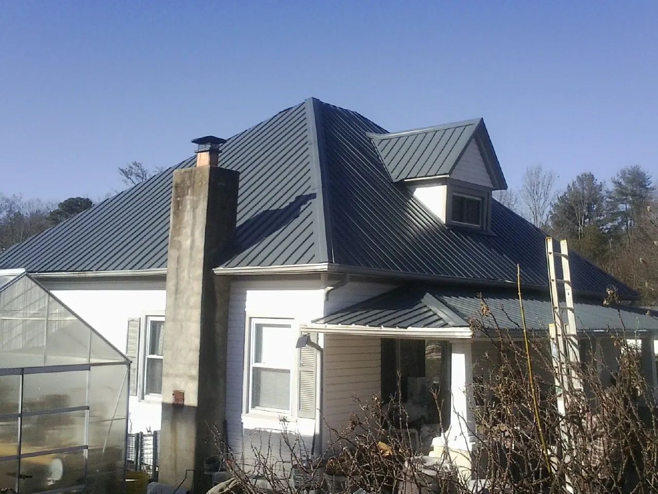 Dark blue standing seam metal roof on a white farmhouse with dormer — Slate & Tile Roof Repair by Roofing Brothers in Framingham