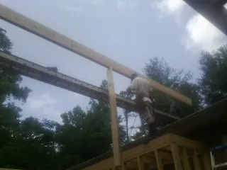 Carpenter setting a ridge beam over a new addition frame — Ice Dam Removal by Roofing Brothers in Framingham