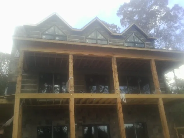 Dormers and porch framing on a large log home under construction — Roof Coating work by our crew in Framingham