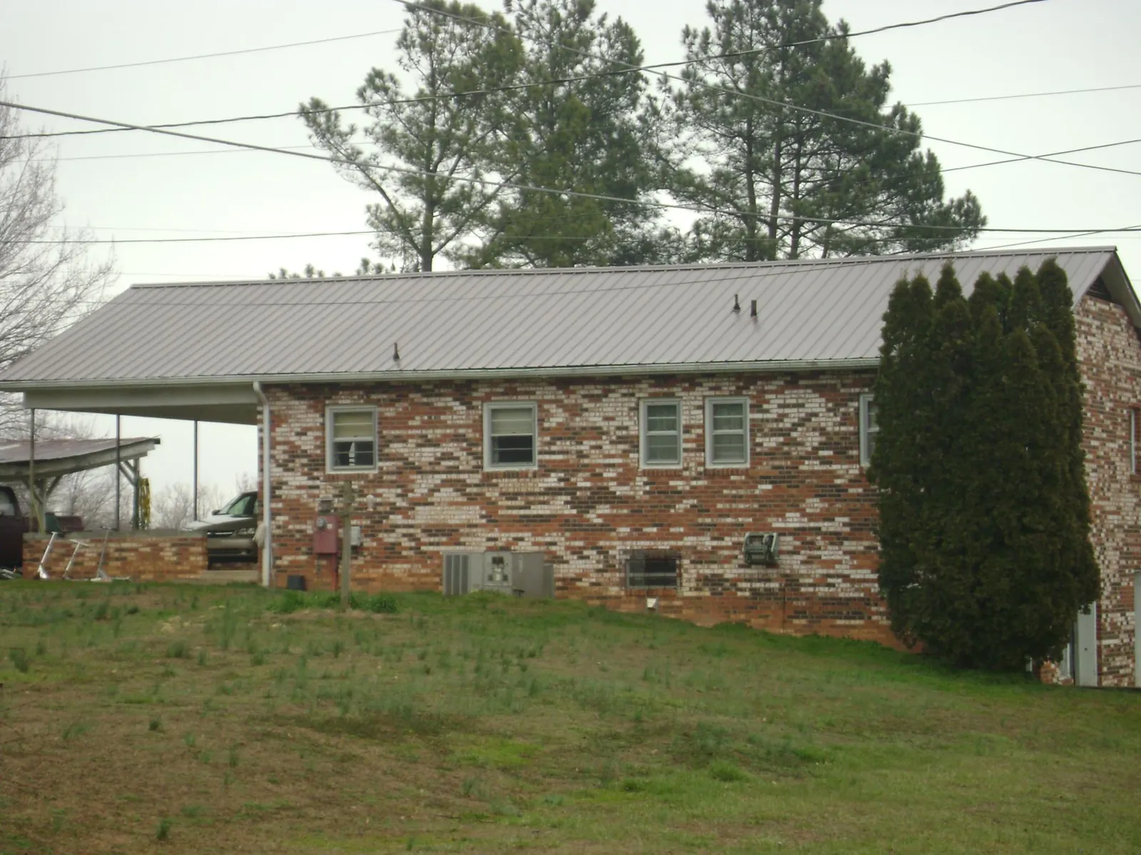 Gray metal roof on a brick split level home with a carport in Framingham