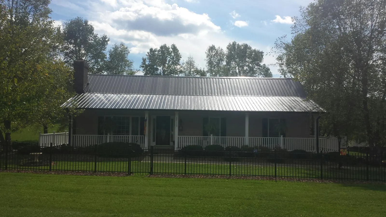 Gray metal roof on a brick ranch with a full width front porch — Gutter Guard Installation work by our crew in Framingham