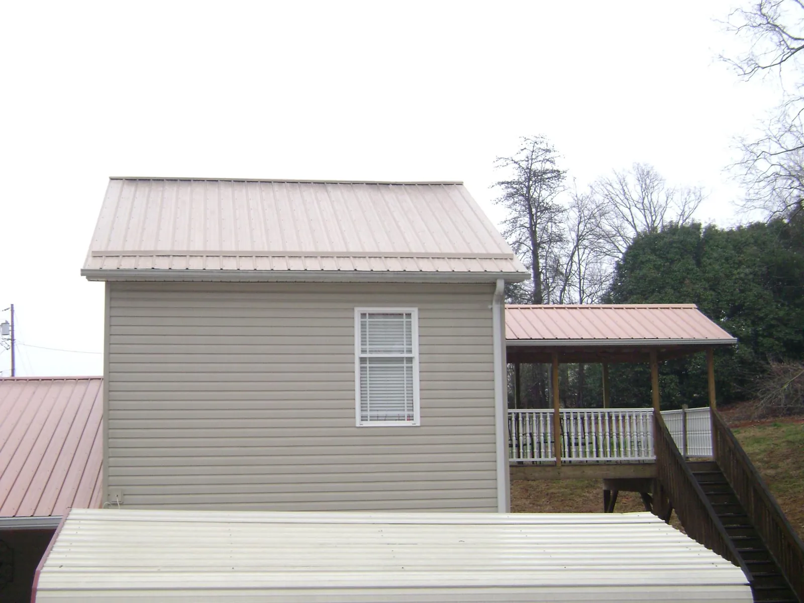 Tan metal roofs on a two story addition and attached porch, from a Roof Replacement job in Framingham