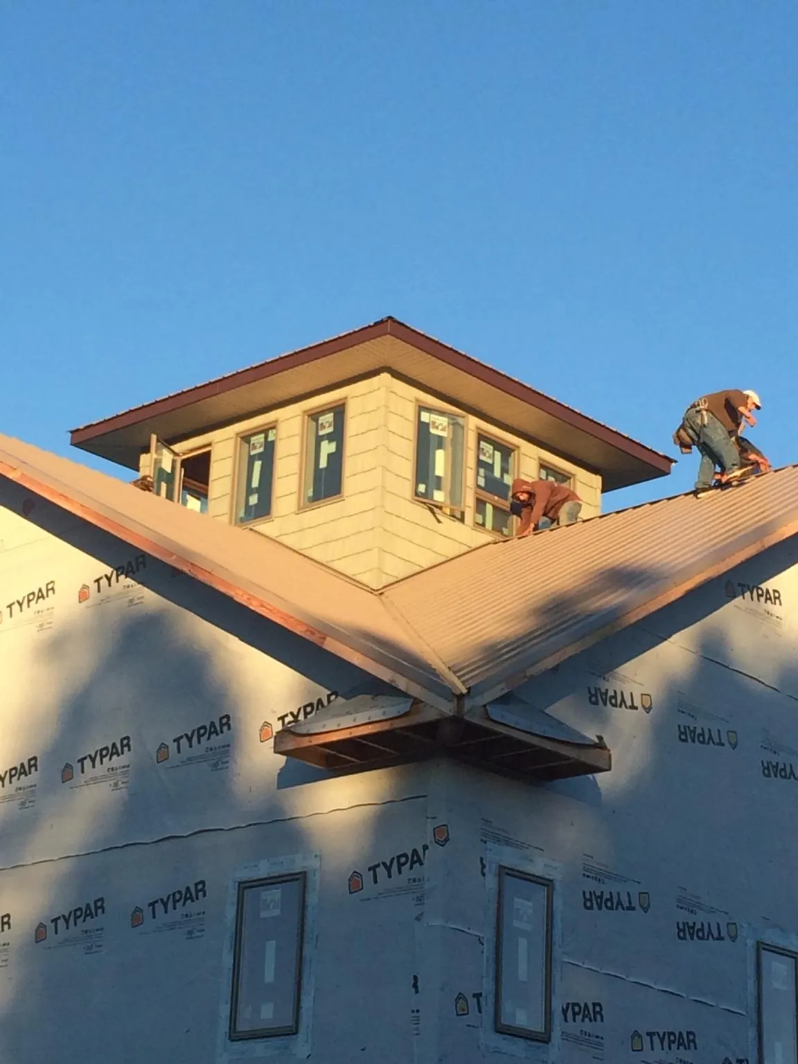 Roofers working around a rooftop cupola on a new metal roof at sunset — Roof Waterproofing in Framingham by Roofing Brothers